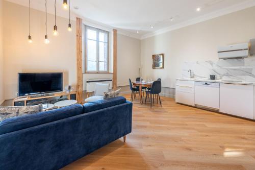 un salon avec un canapé bleu et une cuisine dans l'établissement Smartstay L Ecrin Aix Les Bains, à Aix-les-Bains