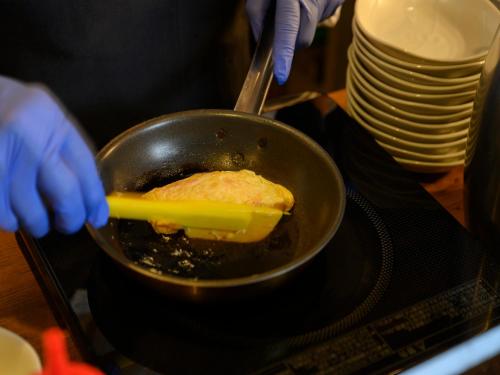 a person cooking food in a pan on a stove at Dormy Inn Toyama Natural Hot Spring in Toyama