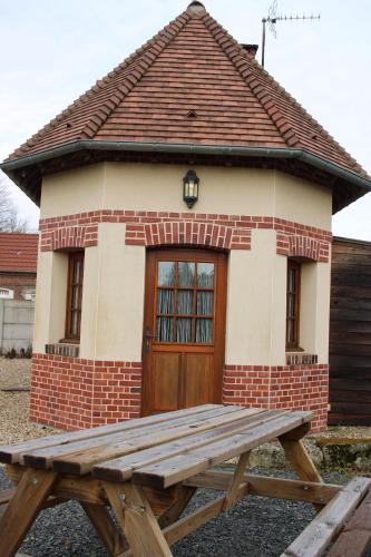 a wooden picnic table in front of a small building at La charmeuse in Tocqueville