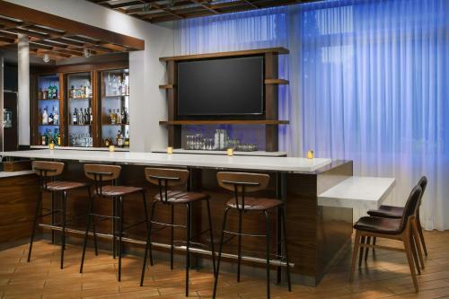 a bar with stools and a flat screen tv at Courtyard by Marriott Los Angeles Woodland Hills in Woodland Hills