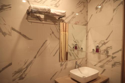 a white bathroom with a sink and a mirror at Lotus Resort in Raipur
