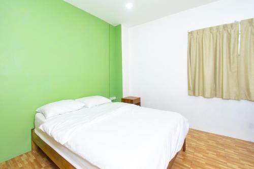 a bedroom with a white bed and a green wall at Tom Guest House ทอมส์ เกสต์เฮ้าส์ in Thung Maha Mek