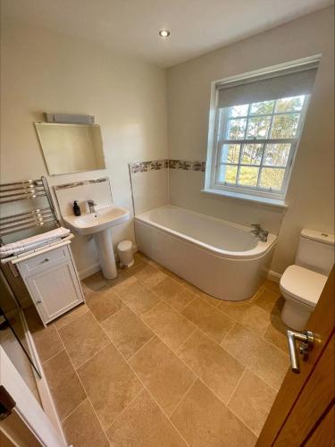 a bathroom with a tub and a sink and a toilet at Sherrabeg Cottage in Laggan
