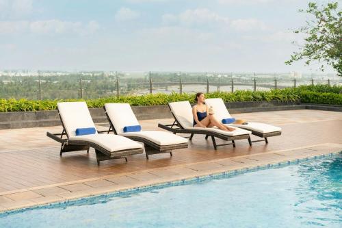 a woman sitting in lounge chairs next to a swimming pool at Sheraton Can Tho in Can Tho