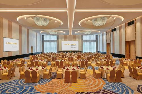 a large banquet hall with tables and chairs and a screen at Courtyard by Marriott Setia Alam in Setia Alam