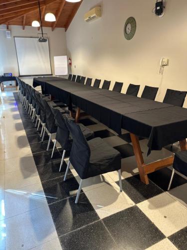 a long black table and chairs in a room at Garden House Hotel in Río Cuarto