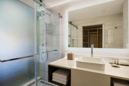 a bathroom with a sink and a glass shower at Renaissance St. Augustine Historic Downtown Hotel in Saint Augustine