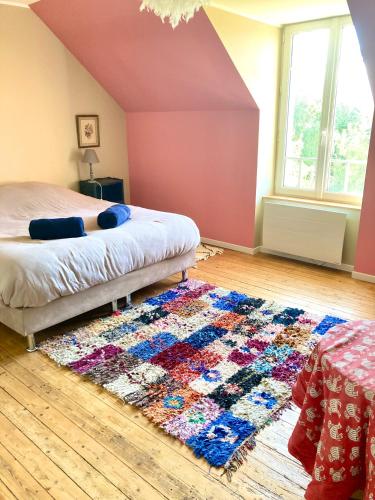 a bedroom with a bed and a rug on the floor at Longère 12 couchages Ploubalay in Ploubalay