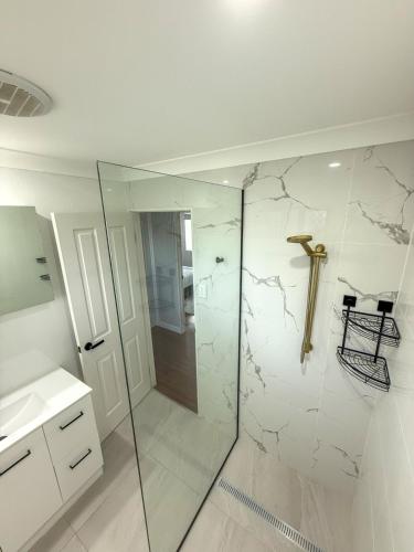 a white bathroom with a shower and a sink at Chic Retreat Vintage and Modern in Garbutt Station