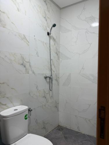 a white bathroom with a toilet and a shower at Playa Surf House in Tamraght Ouzdar