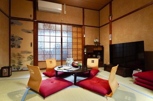 a living room with a table and chairs and a tv at Gomakubo in Osaka