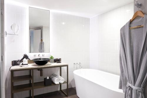 a white bathroom with a tub and a sink at Pier One Sydney Harbour, Autograph Collection in Sydney