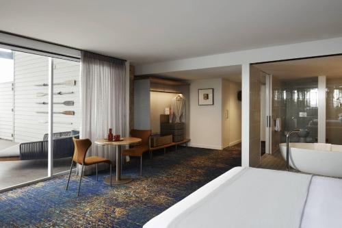 a hotel room with a tub and a bedroom at Pier One Sydney Harbour, Autograph Collection in Sydney