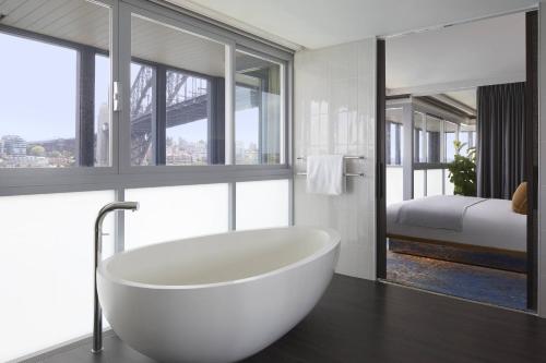 a bathroom with a bath tub and a bedroom at Pier One Sydney Harbour, Autograph Collection in Sydney