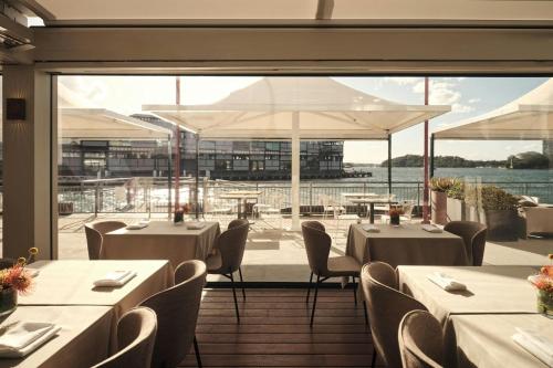 a restaurant with tables and chairs and a large window at Pier One Sydney Harbour, Autograph Collection in Sydney