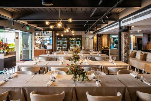 a restaurant with white tables and chairs and a bar at Pier One Sydney Harbour, Autograph Collection in Sydney