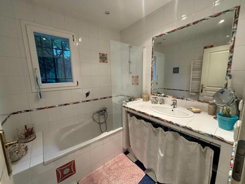 une salle de bain avec une baignoire, un lavabo et un miroir dans l'établissement villa paisible en pleine nature 7km des plages Cannes Mandelieu, à Pégomas