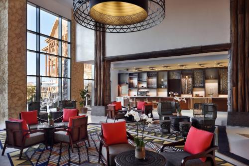a lobby of a hotel with red chairs and tables at Lapita, Dubai Parks and Resorts, Autograph Collection in Dubai