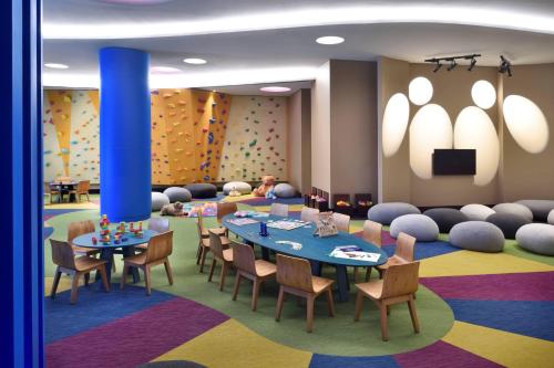a waiting room with tables and chairs and a tv at Lapita, Dubai Parks and Resorts, Autograph Collection in Dubai