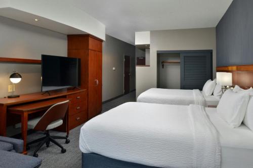 a hotel room with two beds and a desk and a television at Courtyard by Marriott Harrisburg Hershey in Harrisburg