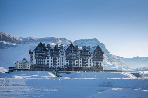 a large building in the snow with mountains behind it at Park Chalet, Shahdag, Autograph Collection in Shahdag