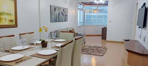 a dining room with a table with chairs and a television at Apto 3 Quartos com Suíte e 3 Banheiros em Guarapari in Guarapari
