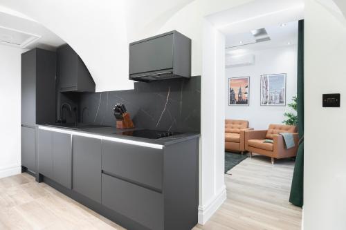 a kitchen with a black counter and a living room at LONDONERS - Harley Street Serviced Apartments in London