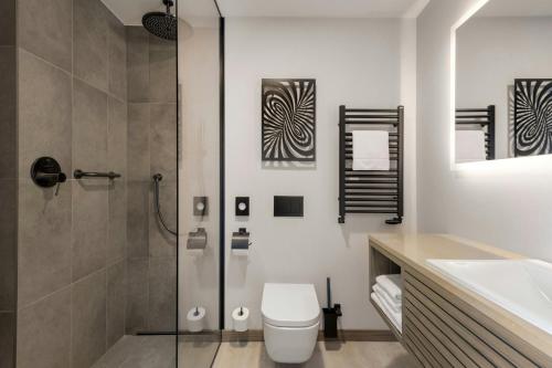 a bathroom with a shower and a toilet and a sink at AC Hotel by Marriott Krakow in Kraków