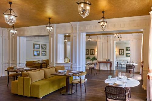 a restaurant with a yellow couch and tables and chairs at Grotta Giusti Thermal Spa Resort Tuscany, Autograph Collection in Monsummano