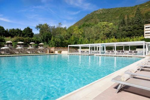 a large swimming pool with chairs and a mountain at Grotta Giusti Thermal Spa Resort Tuscany, Autograph Collection in Monsummano