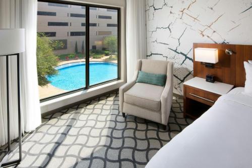 a hotel room with a bed and a chair and a window at Marriott Dallas Allen Hotel & Convention Center in Allen