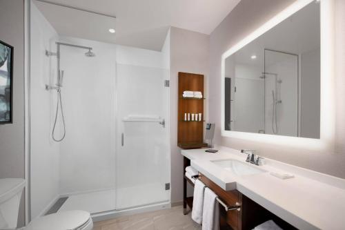 a white bathroom with a sink and a shower at Marriott Dallas Allen Hotel & Convention Center in Allen