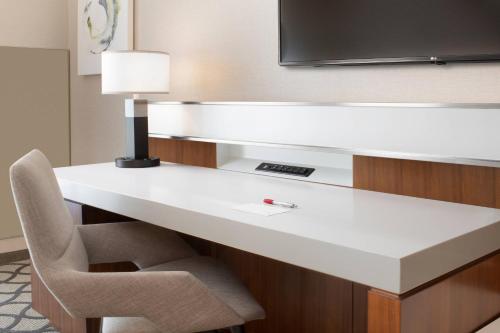 a desk in a hotel room with a chair and a television at Marriott Dallas Allen Hotel & Convention Center in Allen