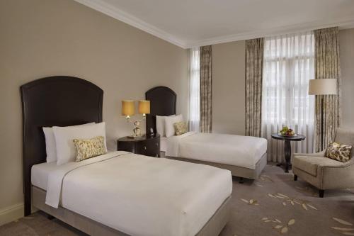 a hotel room with two beds and a chair at JW Marriott Grosvenor House London in London