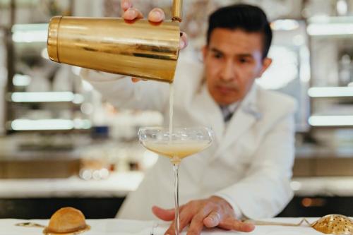 a man pouring a glass of white wine at JW Marriott Grosvenor House London in London
