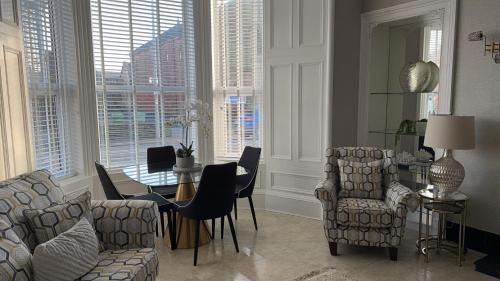a living room with chairs and a table and windows at No 9 Serviced Apartment in Prestwick