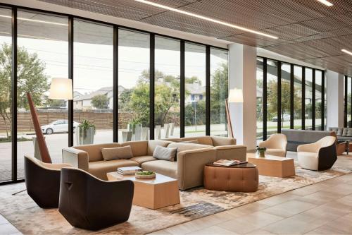 a living room with couches and tables and windows at AC Hotel By Marriott Dallas By The Galleria in Dallas