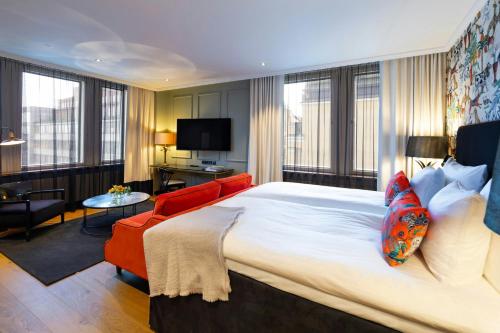 a hotel room with a large bed and a red couch at Hotel U14, Autograph Collection in Helsinki