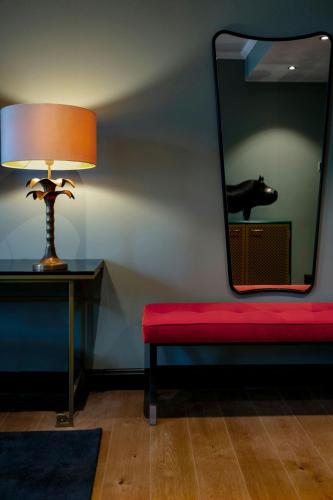 a red bench with a lamp and a mirror at Hotel U14, Autograph Collection in Helsinki