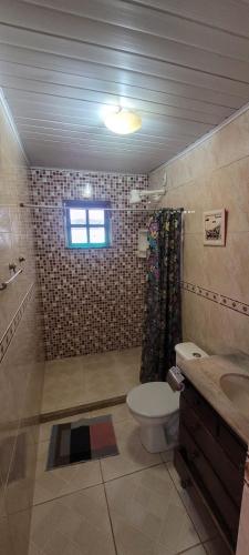 a bathroom with a toilet and a shower and a sink at Vila Hibisco Pousada Saquarema in Saquarema