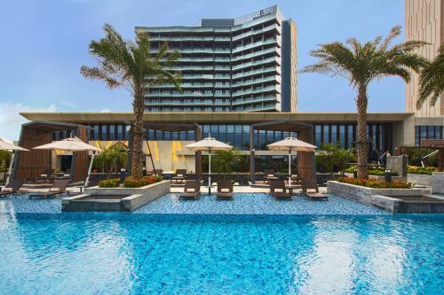 a swimming pool with chairs and umbrellas in front of a building at Renaissance Haikou Hotel in Haikou