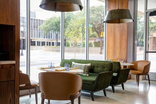 a restaurant with a green couch and tables and windows at Le Meridien Fort Worth Downtown in Fort Worth