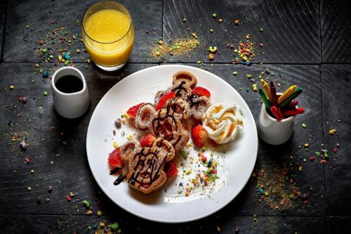 a plate of waffles and strawberries with a glass of orange juice at Anaheim Marriott in Anaheim
