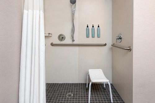 a bathroom with a shower curtain and a stool at Courtyard by Marriott Danbury in Danbury