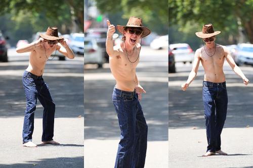 a shirtless man wearing a cowboy hat standing on a street at The Tree House in Johannesburg