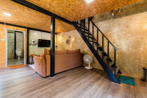 a living room with a couch and a staircase at ไชยพล โฮมสเตย์ หมู่บ้านแม่กำปอง in Ban Pok Nai
