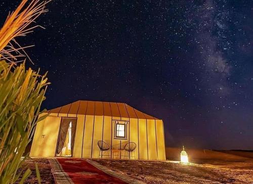 a small house in the desert at night at Merzouga Lovely Luxury Camp in Merzouga