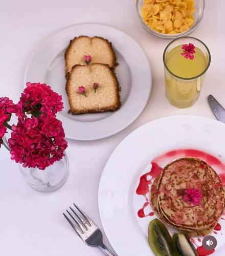 2 Teller mit Essen auf einem Tisch mit Toast und Blumen in der Unterkunft Lefkothea Hotel in Kamari