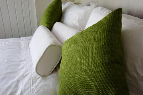 a bed with green and white pillows on it at Villas Sur Mer in Negril