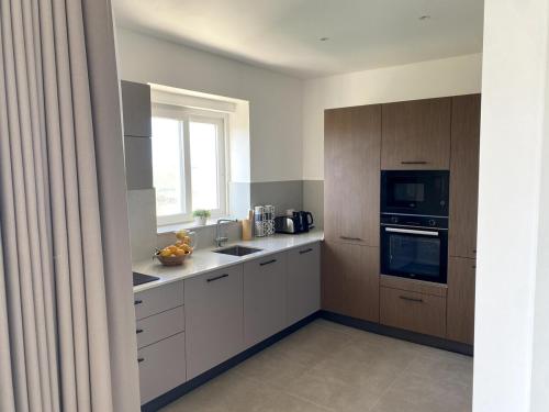 a kitchen with white cabinets and a window at The Valley Collection - Suite A22 in Xagħra